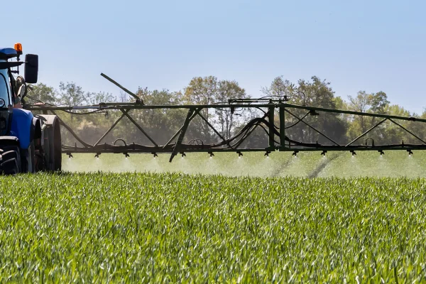 Foto colorida de campo verde e máquina operando agrotóxicos - Metrópoles.
