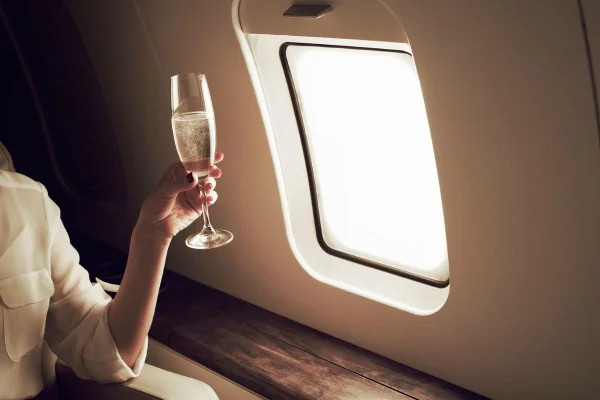 mulher segurando uma taça de champagne no avião