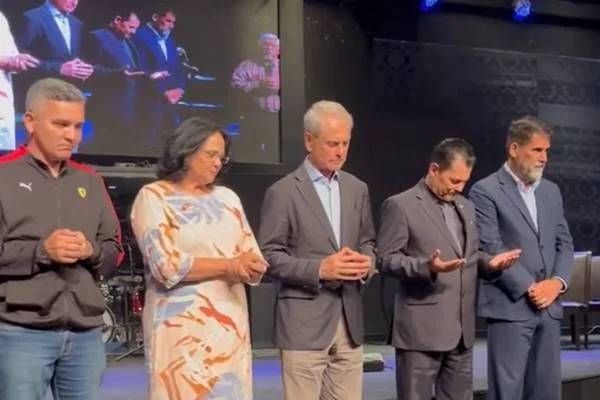 Imagem colorida de quatro homens e uma mulher orando
