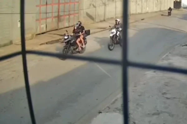Imagem colorida mostra policial perseguindo dois suspeitos de moto. Metrópoles
