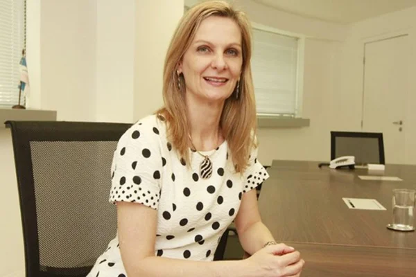Imagem de Ana Paula Vescovi, economista-chefe do Santander. Ela veste uma blusa branca com detalhes pretos, tem cabelo loiro e está posando para foto, sorridente - Metrópoles