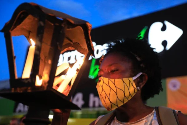 mulher negra com vela em frente ao Carrefour