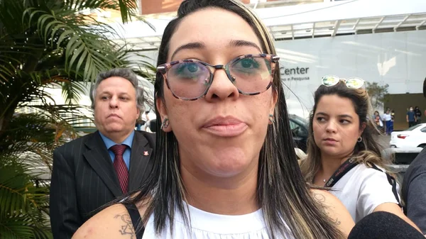 Imagem mostra mulher de óculos à frente de outras duas pessoas - Metrópoles