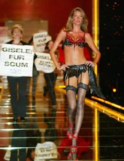 Manifestantes protestam enquanto a modelo Gisele Bündchen (à direita) desfila durante o Victoria’s Secret Fashion Show, realizado no Lexington Avenue Armory, em 14 de novembro de 2002, em Nova York Manifestantes protestam enquanto a modelo Gisele Bündchen (à direita) desfila durante o Victoria’s Secret Fashion Show, realizado no Lexington Avenue Armory, em 14 de novembro de 2002, em Nova York