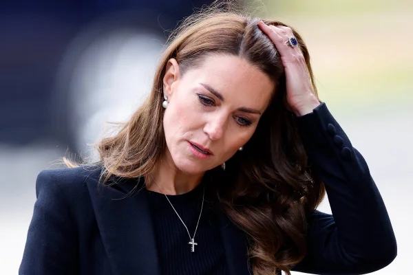Foto colorida de mulher passando a mão no cabelo. Ela veste uma roupa preta - Metrópoles