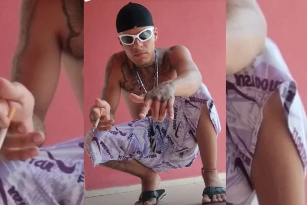 Homem tatuado sem camisa, agachado, usando bermuda - Metrópoles