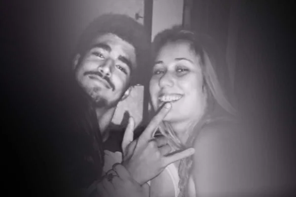 Na imagem em preto e branco, um homem e uma mulher estão posicionados no centro