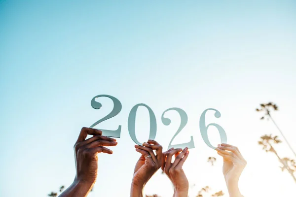 Foto colorida mãos de pessoas segurando o número 2026