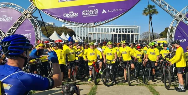 ciclistas perfilados vestidos com roupas amarelas e com prédio ao fundo