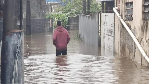 Imagem colorida de homem andando em rua alagada - Metrópoles