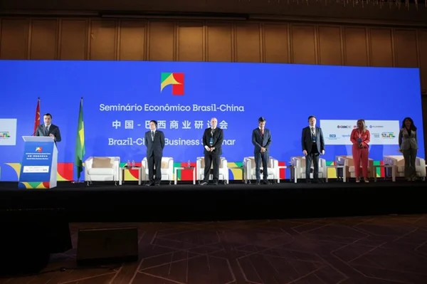 Imagem colorida mostra pessoas se apresentando em seminário durante visita do Brasil à China