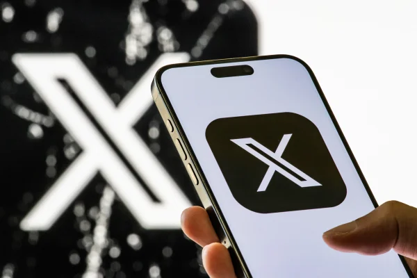 Nesta foto ilustrativa, um smartphone exibe o ícone atualizado do aplicativo X, com fundo preto, enquanto a versão anterior do logotipo X é vista ao fundo