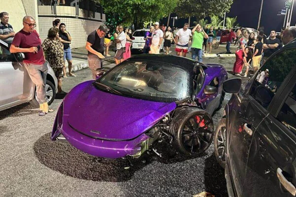 imagem colorida mostra mc laren de cor roxa colidido com carro sandero de cor preta - Metrópoles