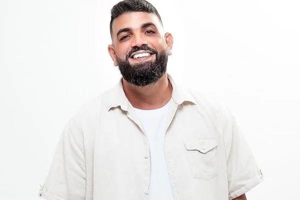 Messias Soares posa sorridente com um look todo branco - Metrópoles