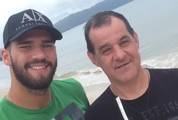 Foto colorida de goleiro Alisson com o pai - Metrópoles
