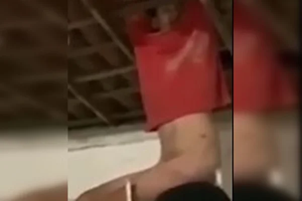 Imagem mostra suspeito de tentar invadir comércio preso em telhado. Ele está sem a parte de baixo das roupas e usa apenas uma camiseta vermelha - Metrópoles