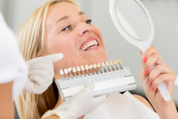Consultório de dentista de odontologia cosmética - mulheres na casa dos 30 anos com longos cabelos loiros deitadas na cadeira antes de receberem atendimento odontológico e branqueamento de dentes, clareamento dental. Metrópoles