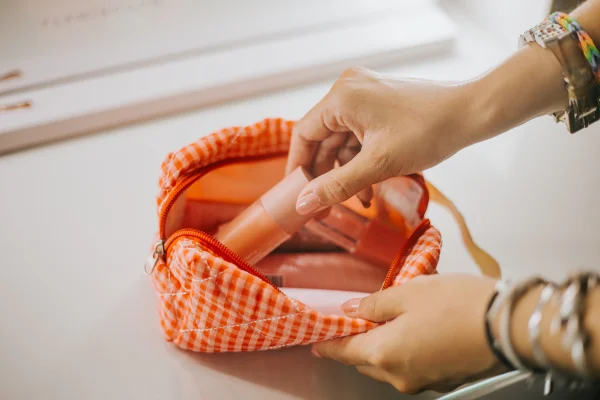 Foto colorida de mão feminina colocando item em nécessaire