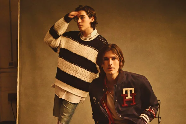 Modelo usa suéter branco com preto. Outro modelo usa casaco estilo colegial e camiseta de listras - Metrópoles