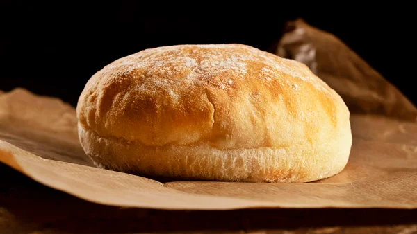 Imagem de pão redondo em cima de folhas de papel pardo