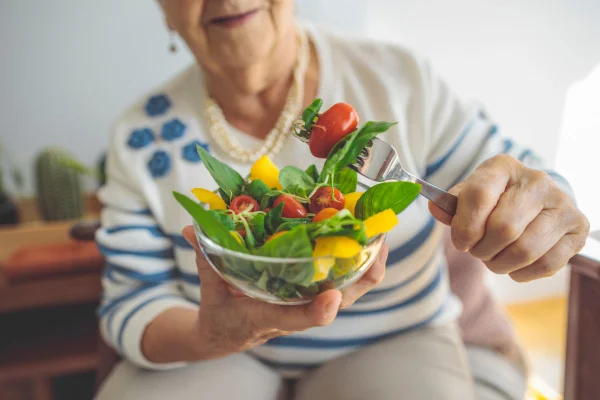 mulher de cabelos brancos comendo uma salada
