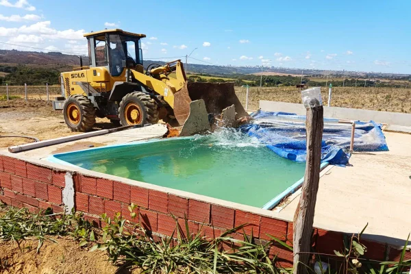 Foto colorida de trator derrubando piscina