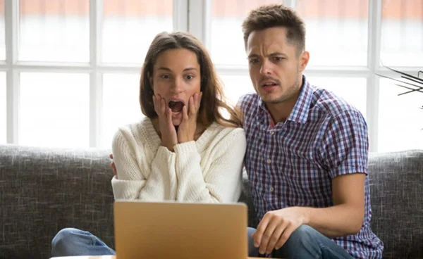 casal chocado em frente ao omputador