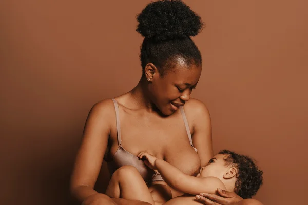 Foto colorida de mãe amamentando seu bebê - Metrópoles.