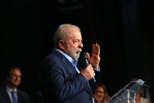 O presidente eleito Lula em coletiva de impresa para anúncio de novos ministros para o próximo governo. Ele fala em púlpito diante de microfone - Metrópoles
