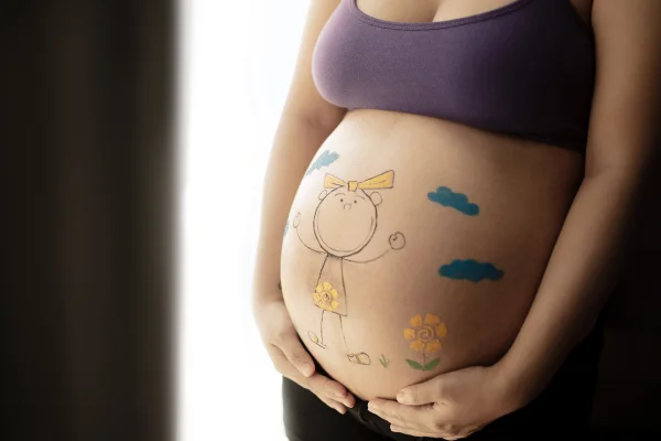 Foto colorida da barriga de uma mulher grávida com desenhos nela - Metrópoles