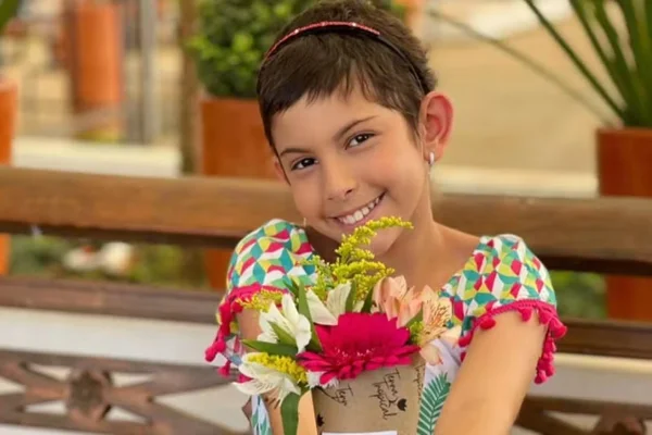 Lorena Torezan Viviani posa, sorridente, com uma roupa florida e um buquê nas mãos - Metrópoles