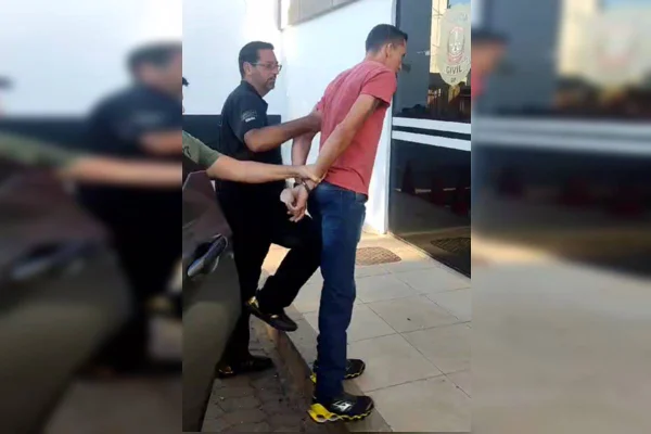 Foto colorida de agentes levando suspeito para o cárcere