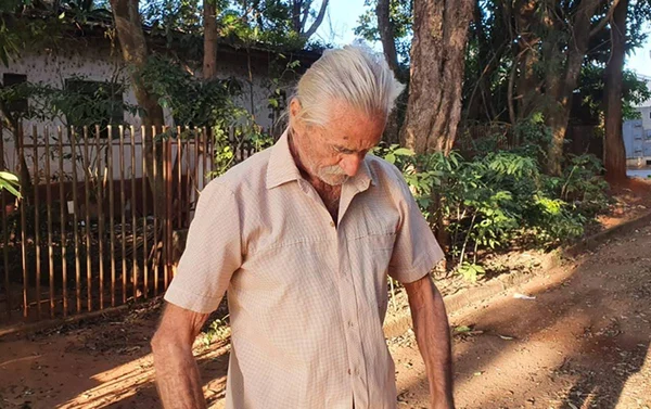 idoso olha para baixo enquanto veste camisa