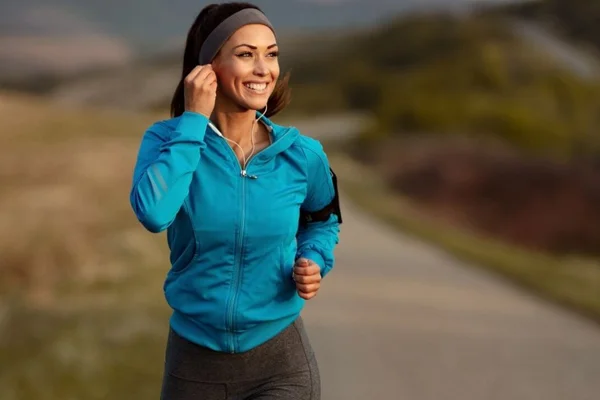 Mulher fazendo corrida em uma estrada com uma camisa azul - Metrópoles