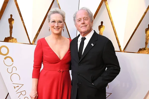 Foto colorida de Meryl Streep e Don Gummer no tapete vermelho do Oscar 2018. Ela veste um vestido vermelho, ele um terno preto - Metrópoles
