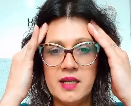 Em foto colorida mulher de óculos apoio dedos de ambas as mãos na testa - Metrópoles