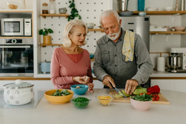 Foto de um casal maduro feliz cortando vegetais enquanto cozinham juntos em casa. Conceito de envelhecer saudável