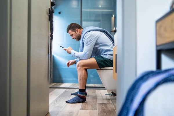 Foto colorida de homem usando celular enquanto usa o vaso sanitário - Metrópoles.