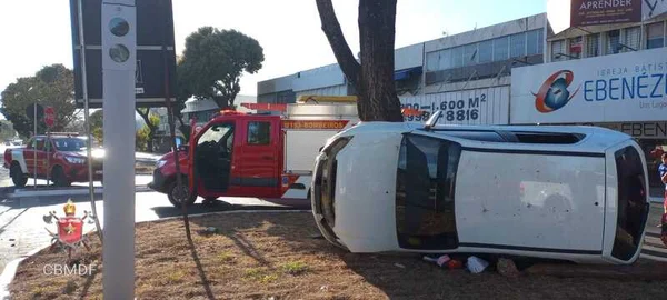 Carro branco capotado no gramado