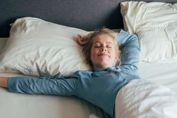 Foto colorida de mulher deitada na cama após boa noite de sono -Metrópoles.