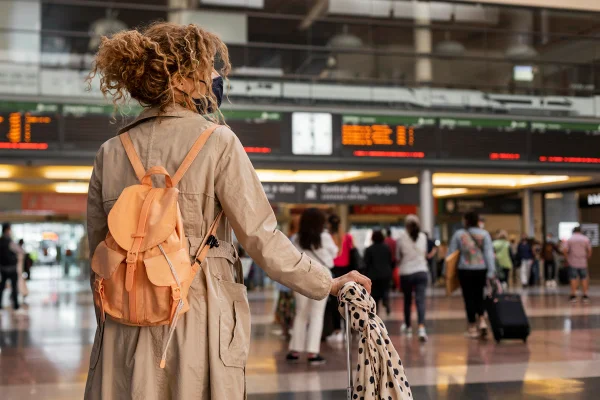 Foto em plano médio mostrando uma mulher de costas em um aeroporto. Viagem. Metrópoles