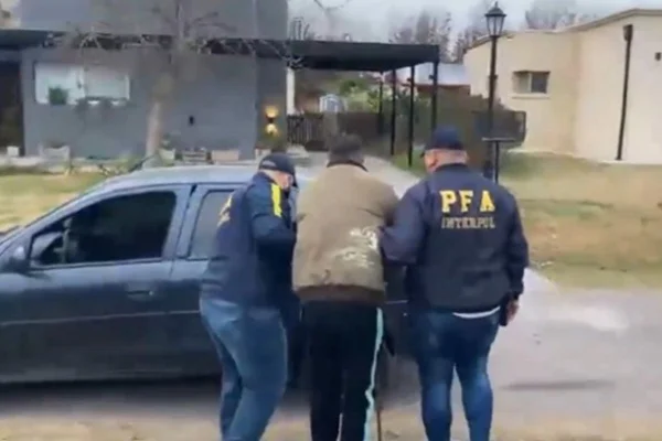Imagem colorida mostra dois policiais argentinos conduzindo um homem para um carro - Metrópoles