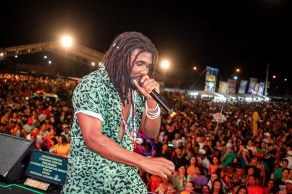 Homem negro com tranças canta para uma plateia lotada