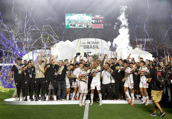 Imagem colorida dos jogadores levantando a taça - Metrópoles