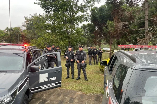 Imagem colorida mostra dois carros da Rota parados, entre eles está um grupo de policiais fardados, de pé - Metrópoles