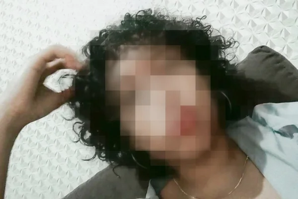 Menina de cabelos crespos e curtos coloca a mão na cabeça e veste blusa cinza