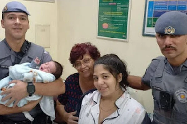 foto colorida de dois PMs, familiares e bebê salvo após engasgar em casa, na zona leste - Metrópoles