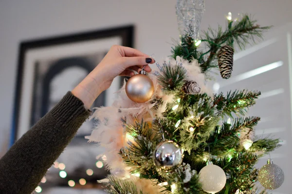 Dedo de mulher colocando enfeite de Natal em árvore - Metrópoles
