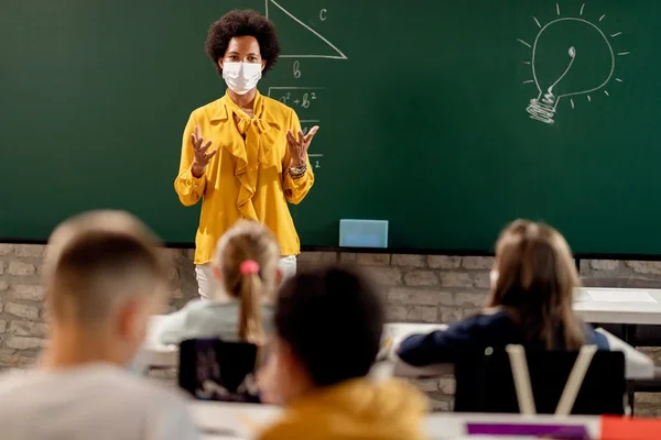 professora dando aula com máscara de proteção