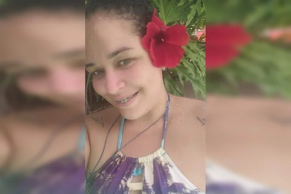 Mulher branca com flor vermelha na orelha, sorrindo